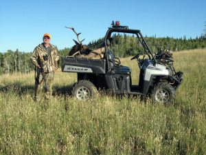 Hunter with his Elk in a back of a Polaris in a meadow