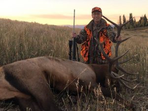 Hunter with his Elk in meadow